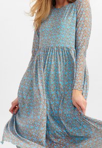 Šaty s dlouhým rukávem z lehké tkaniny, s modro-hnědým květinovým vzorem, s nařaseným pasem a splývavým střihem.