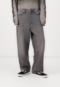 Sive jeans z relaxed krojem, ki vključujejo klasi�čen pet žepni dizajn in rahlo zbledel videz. V kombinaciji s črnimi supergami.