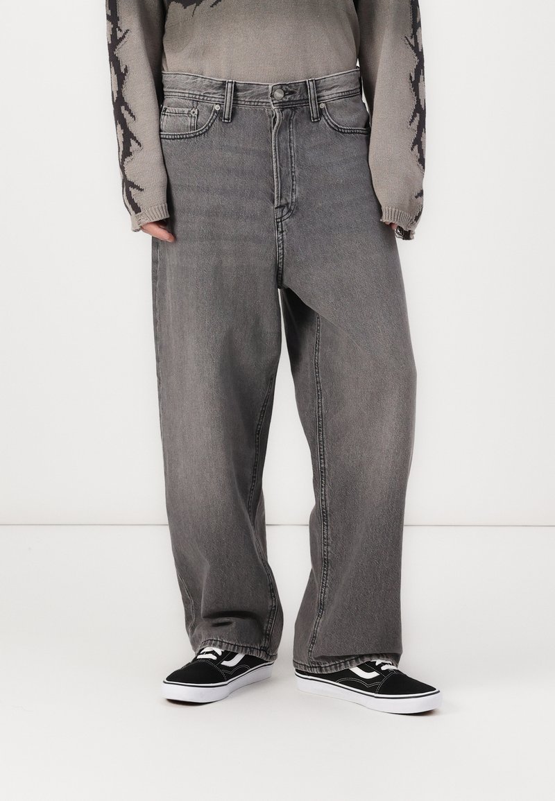 Sive jeans z relaxed krojem, ki vključujejo klasičen pet žepni dizajn in rahlo zbledel videz. V kombinaciji s črnimi supergami.