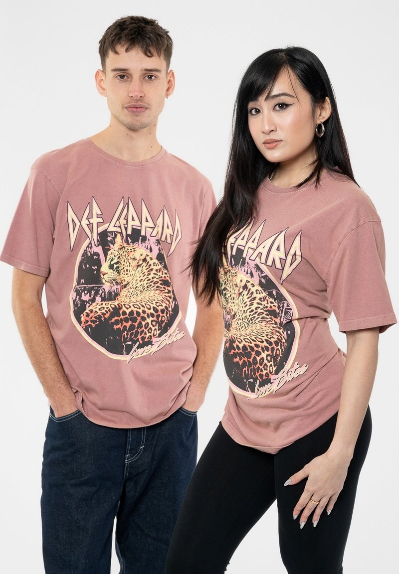 Pink graphic t-shirts featuring a leopard illustration and “Def Leppard” text. Short sleeves, crew neck, relaxed fit. Worn by two models.
