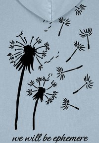 Svetlomodrá mikina s čiernymi ilustráciami púpav a plávajúcich semien. Text pod tým znie "budeme efemérni."