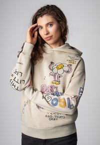 Crèmekleurige hoodie met een trekkoord, voorzien van kleurrijke grafische ontwerpen en teksten, waaronder bloemen en zinnen, met ribbelboorden en -zoom.