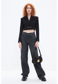 Blazer negro corto con botones dorados, combinado con unos vaqueros de mezclilla oscura de tiro alto con costuras plateadas, llevando un bolso negro con detalles dorados.