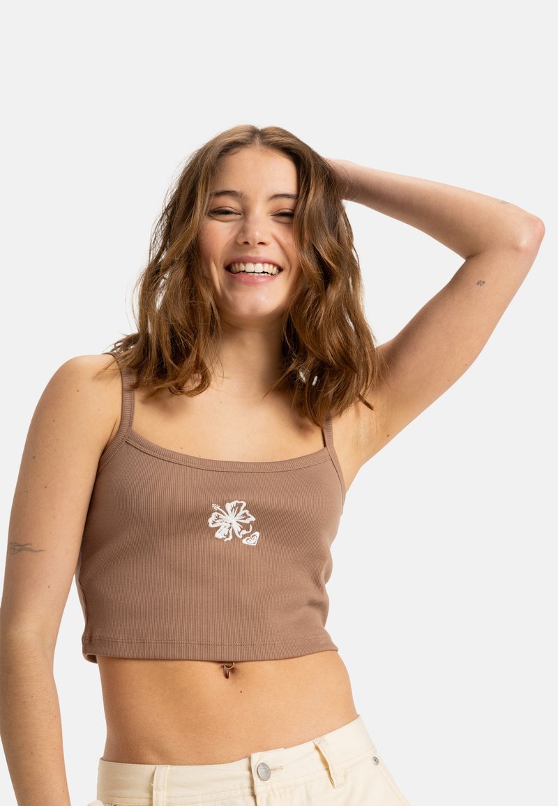 Bruine geribbelde crop top met dunne bandjes en witte bloemenborduursel op de voorkant. Glad textuur, strakke pasvorm en cropped lengte.