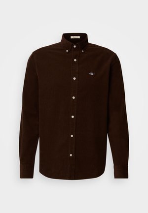 Brun corduroy skjorte med lange ærmer, knap-ned krave og hvide knapper. Udstyret med et lille broderet logo på brystet.