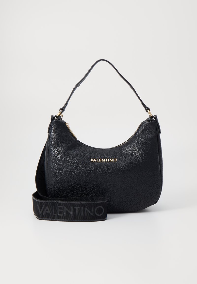 Black leather handbag with a textured finish, curved shape, top zip closure, and gold hardware. Features a detachable branded strap.
