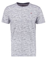 T-shirt gris à manches courtes avec une texture chinée, col rond et un petit logo rouge sur le côté gauche de la poitrine.