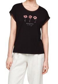 Camiseta negra de manga corta con cuello redondo que presenta tres diseños florales en rosa y el texto "HERMOSA como siempre" abajo. Textura suave.