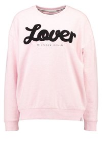 Roze sweatshirt van zachte stof met "Lover" in zwarte, fluffy borduring en de tekst "HILFIGER DENIM" eronder in een standaardlettertype.