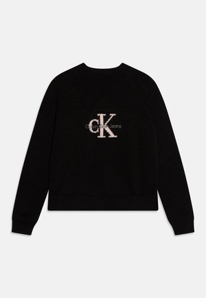 Suéter negro con textura acanalada, que presenta un gran logo tejido "cK" en rosa en el centro. Cuello redondo, mangas largas, diseño corto.