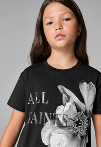 Juodas medvilninis marškinėliai su dideliu baltu gėlių piešiniu ir sidabriniais užrašais "ALL SAINTS" priekyje. TrumpomisRankovėmis ir apvalia iškirpte.