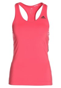 Różowy sportowy top na ramiączkach z wycięciem typu racerback, wykonany z gładkiej tkaniny, z czarnym logo Adidas na lewej części klatki piersiowej.