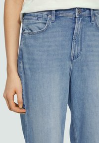 Light blue denim jeans with a relaxed fit, featuring front pockets, a button and zipper closure, and subtle fading on the fabric.