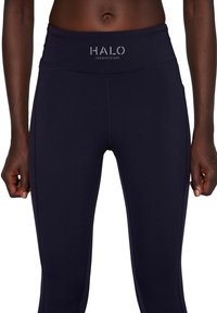 Marineblauwe sportleggings van soepel, rekbaar materiaal. Voorzien van een hoge tailleband met zilveren "HALO" logo en platte naden voor comfort.