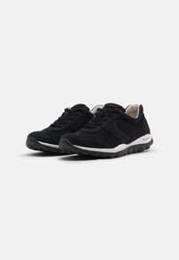 Zwarte sportieve schoenen van mesh en suede, met een vetersluiting, textuuroppervlakken en een witte tussenzool met een flexibele rubberen outsole.