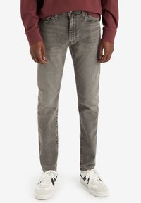 Grå denimjeans med en urtvättad finish, slim fit, fem fickor och kontrasterande sömmar, ihop med vita och svarta sneakers.