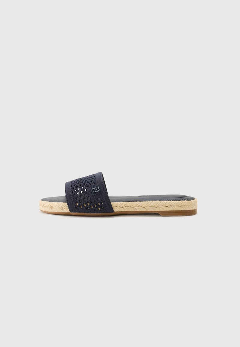 Sandalha azul marinho sem fechos, com parte superior perfurada, sola de juta trançada e sola de borracha. Apresenta um design plano para fácil calce.