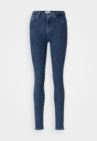 Tanke traperice u tamnoplavom denimu. Imaju pet džepova, petlje za remen i zatvaranje na zip. Blago izblijedjeli izgled s klasičnim krojem kroz noge.