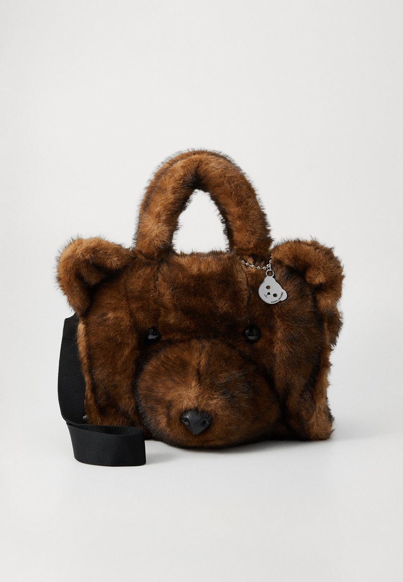 Brun faux fur håndtaske formet som et teddy-bjørn ansigt med sort skulderrem og lille sølv bjørneformet vedhæng.