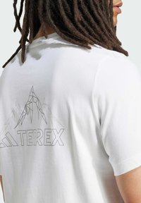 White cotton t-shirt featuring a geometric mountain design and the word "TERREX" printed in bold lettering on the back.