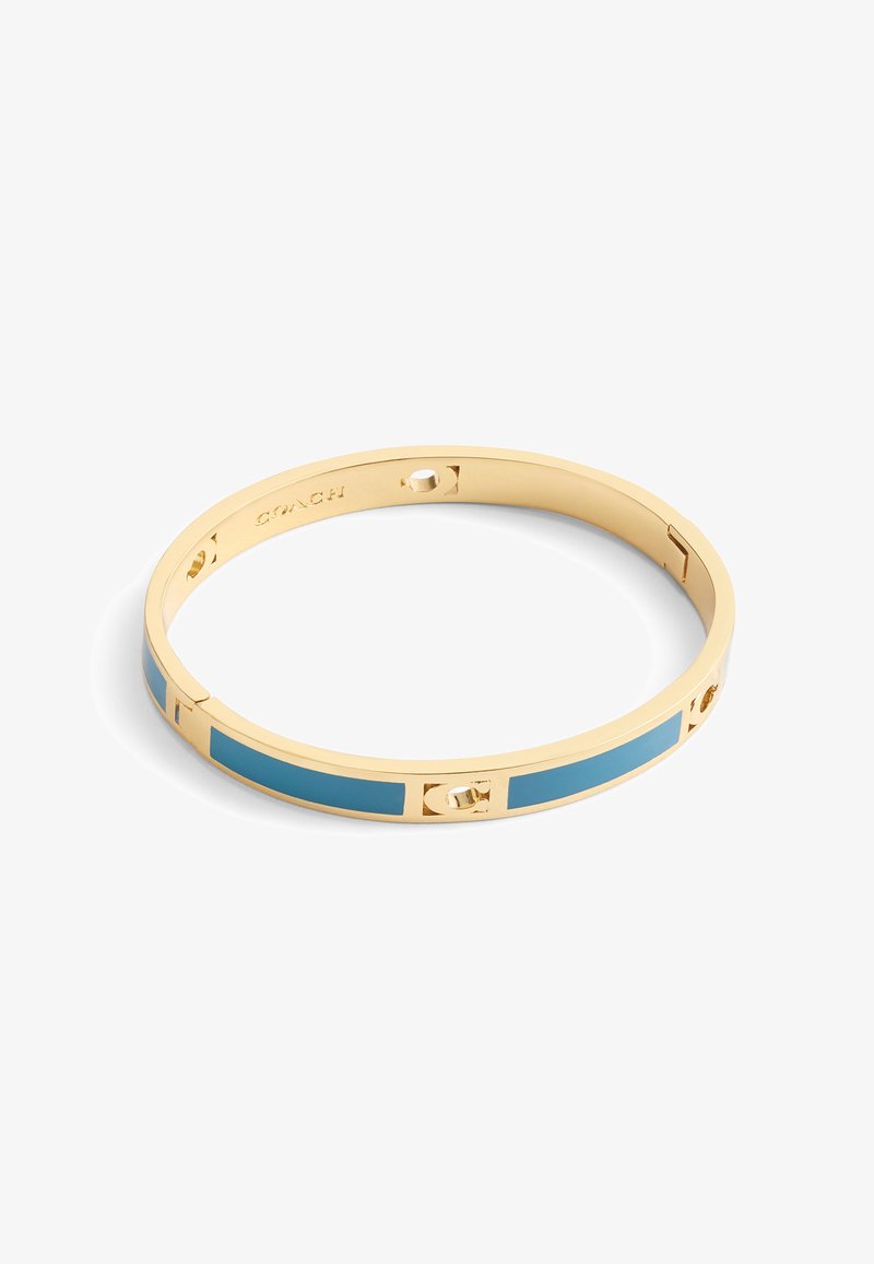 Bracelet jonc en doré avec une finition lisse, accents bleus en incrustation et découpes circulaires. Design minimaliste avec un mécanisme d'ouverture sécurisé.