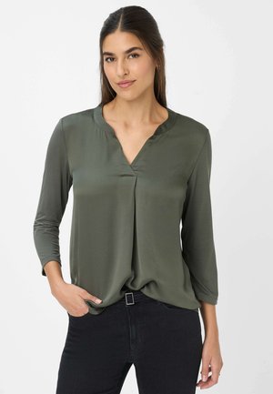 Blusa verde oliva con scollatura a V e maniche a tre quarti, realizzata in un materiale morbido, con una piega al centro per un tocco di design in più.