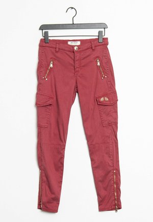 Rote Cargo-Hose in schmaler Passform mit Reißverschlusstaschen vorne, Klapptaschen an den Seiten und Reißverschlüssen an den Knöcheln, hängend an einem schwarzen Bügel.