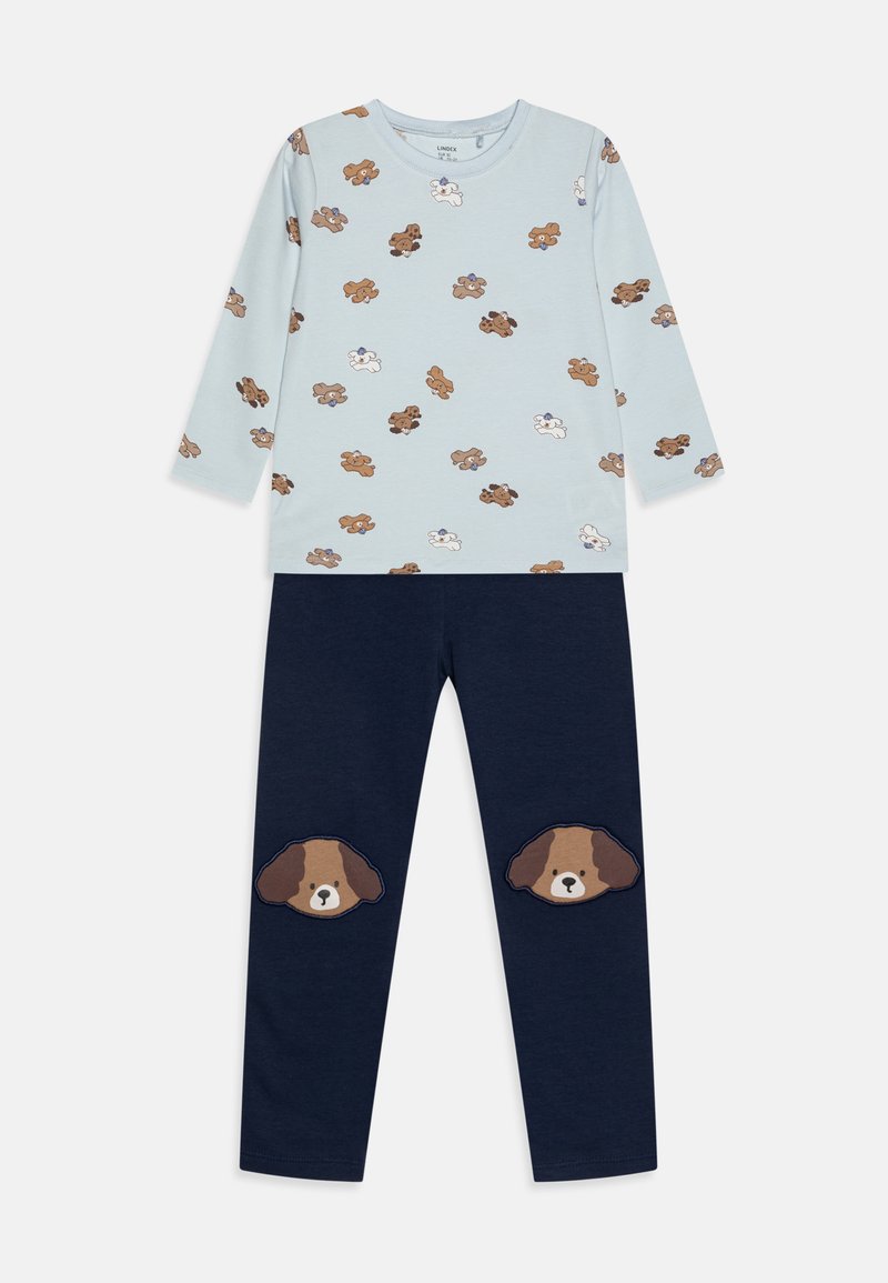 Light blue long-sleeve shirt with small brown and white dog prints, paired with dark navy pants featuring brown dog face patches at the knees.