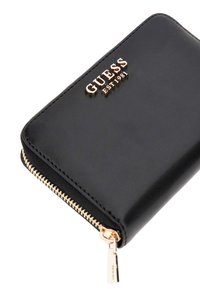 Porte-monnaie en cuir noir avec accessoires en ton or. Comprend une fermeture zippée, un logo embossé et une texture lisse. Design rectangulaire compact.