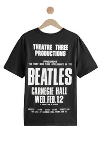 Schwarzes Baumwoll-T-Shirt mit großen weißen Texten, die die Konzertdetails anzeigen: "Beatles", "Carnegie Hall" und "Mi. 12. Feb." deutlich sichtbar.