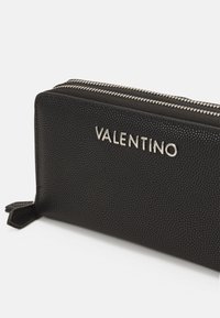 Black leather wallet with a textured exterior, featuring a silver "VALENTINO" logo and two metallic zippers for closure.