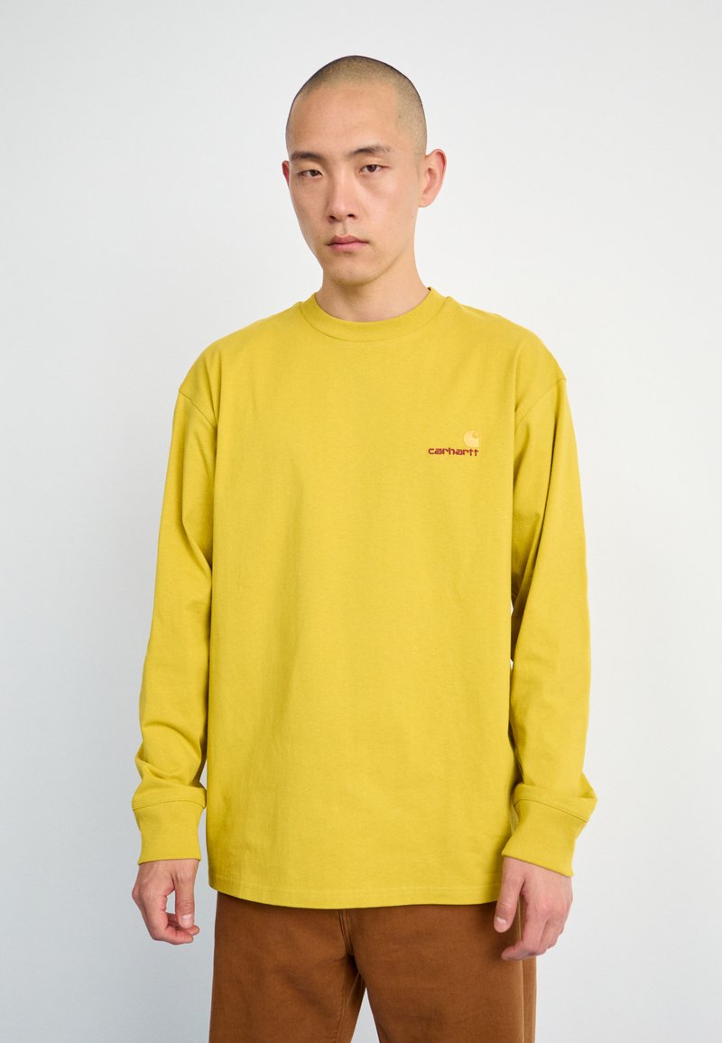 Long-sleeve, mustard-yellow t-shirt made of cotton, features a crew neck, relaxed fit, and small embroidered logo on the chest.