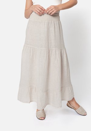 Gonna leggera color beige chiaro, lunga fino alla caviglia, in lino con una vita arricciata e un orlo a balze a strati. Abbinata a scarpe slip-on casual.