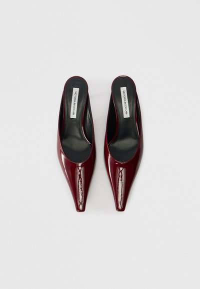 Burgundské lakované muly s špicatými špičkami, otvorenými pätami a čiernymi stielkami. Vyznačujú sa hladkým povrchom a minimalistickým dizajnom.