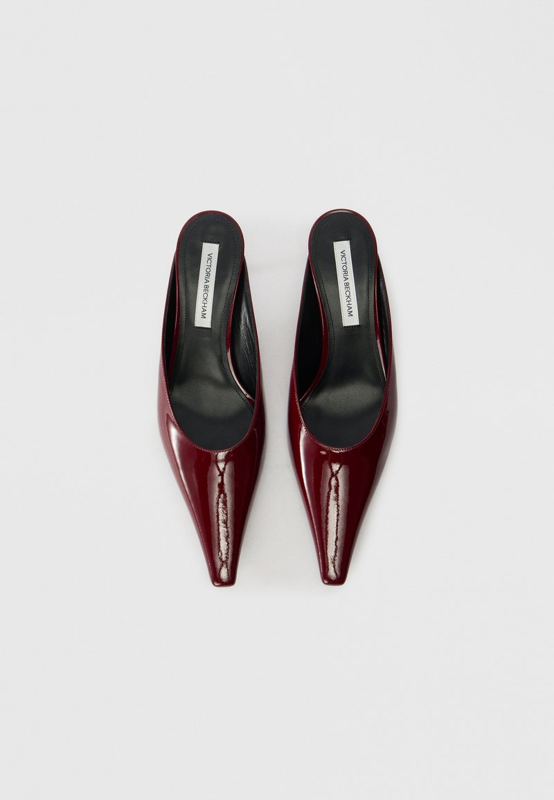 Bordeaux patentlæder mules med spidse tæer, åbne bagdele og sorte indlægssåler. Har en glat overflade og minimalistisk design.