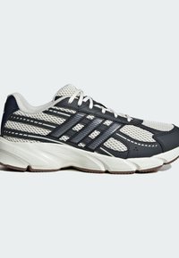 Športové topánky s vrchnou časťou z textilu v bielej a námornej farbe, s čiernymi syntetickými prekrytiami, hrubou bielou medzipodrážkou a gumovou podrážkou.