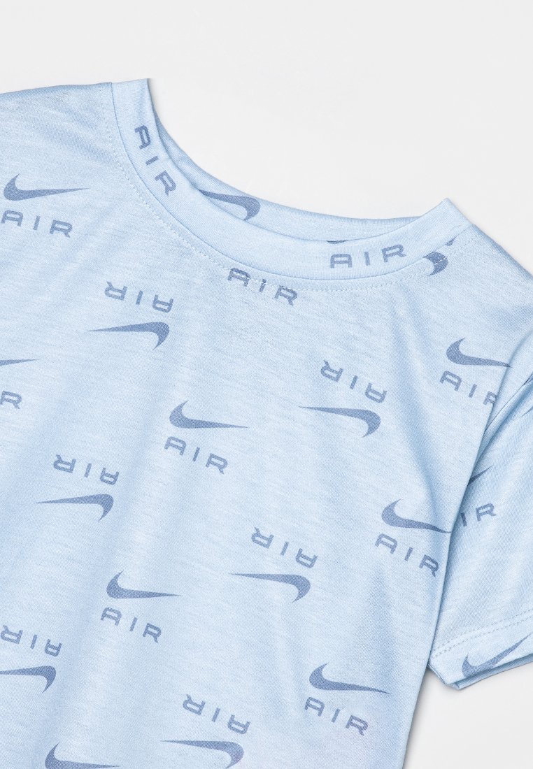 T-shirt bleu clair avec une texture douce, présentant un motif répété de "AIR" et le logo swoosh de Nike en bleu plus foncé. Encolure ronde.