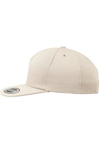 Beige pet met een vlakke rand, gemaakt van stof met een gestructureerd oppervlak. Voorzien van een snapback-sluiting en een cirkelvormig logo-patch aan de zijkant.