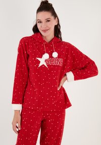 Röd fleece lounge set med huva, prydd med vitt stjärnmönster och texten "SHINE", accentuerad med pom-poms och mjuka vita ärmslut.