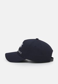 Dark blue baseball cap made of cotton, featuring a stitched logo in white on the front and an adjustable strap at the back.