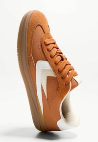 Baskets en daim marron et synthétique orange avec des accents blancs, bout arrondi, lacets texturés et semelle en caoutchouc translucide.