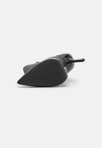 Chaussure à talon haut noire avec un bout pointu, tige en cuir lisse, semelle plate et un talon étroit et rectangulaire. Semelle texturée pour une meilleure adhérence.