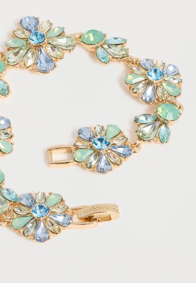 Χρυσό βραχιόλι με συνδεδεμένες ανθικές συστάδες από μπλε, πράσινες και διαφανείς πολύτιμους λίθους σε σχήμα σταγόνας σε λευκό φόντο.