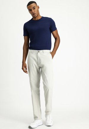 Camisa de manga corta azul marino, pantalones grises claros con cierre de botón y zapatillas blancas. Tela de algodón suave, corte entallado y diseño limpio.