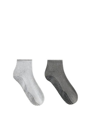 Deux chaussettes antidérapantes longueur cheville, une gris clair et une gris foncé, chacune avec des picots en caoutchouc sous la semelle.