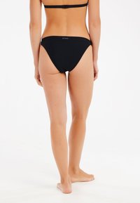 Czarne bikini kąpielowe z umiarkowanym zakryciem, o niskim stanie i małym logotypie z tyłu. Gładka tekstura, minimalistyczny styl.