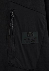 Felpa nera con tasca testurizzata e chiusura con zip, arricchita da un logo in gomma con l'etichetta "WEEKEND OFFENDER". Tessuto morbido opaco.