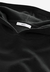 Sort hættetrøje med en bl�ød tekstur, der har en hætte og et synligt mærke med teksten "NEXT." Minimalistisk design med glatte sømdetaljer.