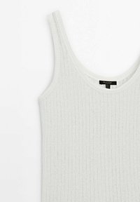 Top in cotone bianco a costine con spalline sottili, caratterizzato da una texture morbida e un collo arrotondato. Etichetta visibile al centro della schiena.