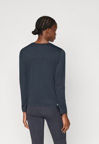 Športová dlhá košeľa s dlhým rukávom v tmavomodrej farbe, s okrúhlym výstrihom, plochými švami a aerodynamickým dizajnom. Materiál s textúrovaným povrchom.